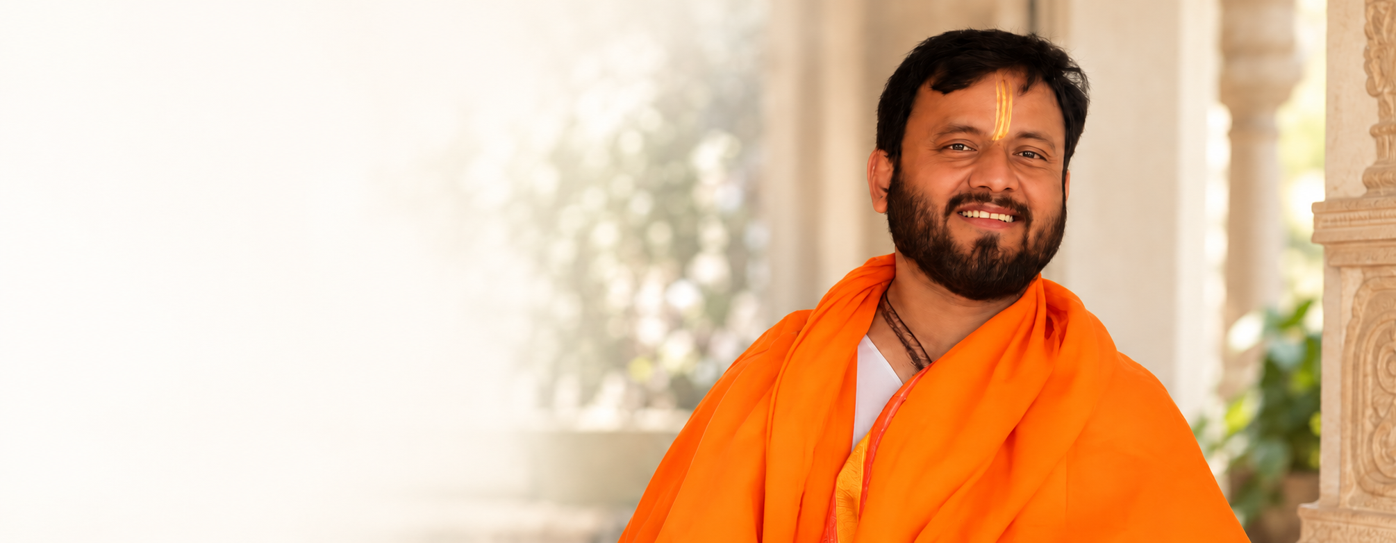 BabuaJi Shukla in saffron clothing against a softly lit temple backdrop